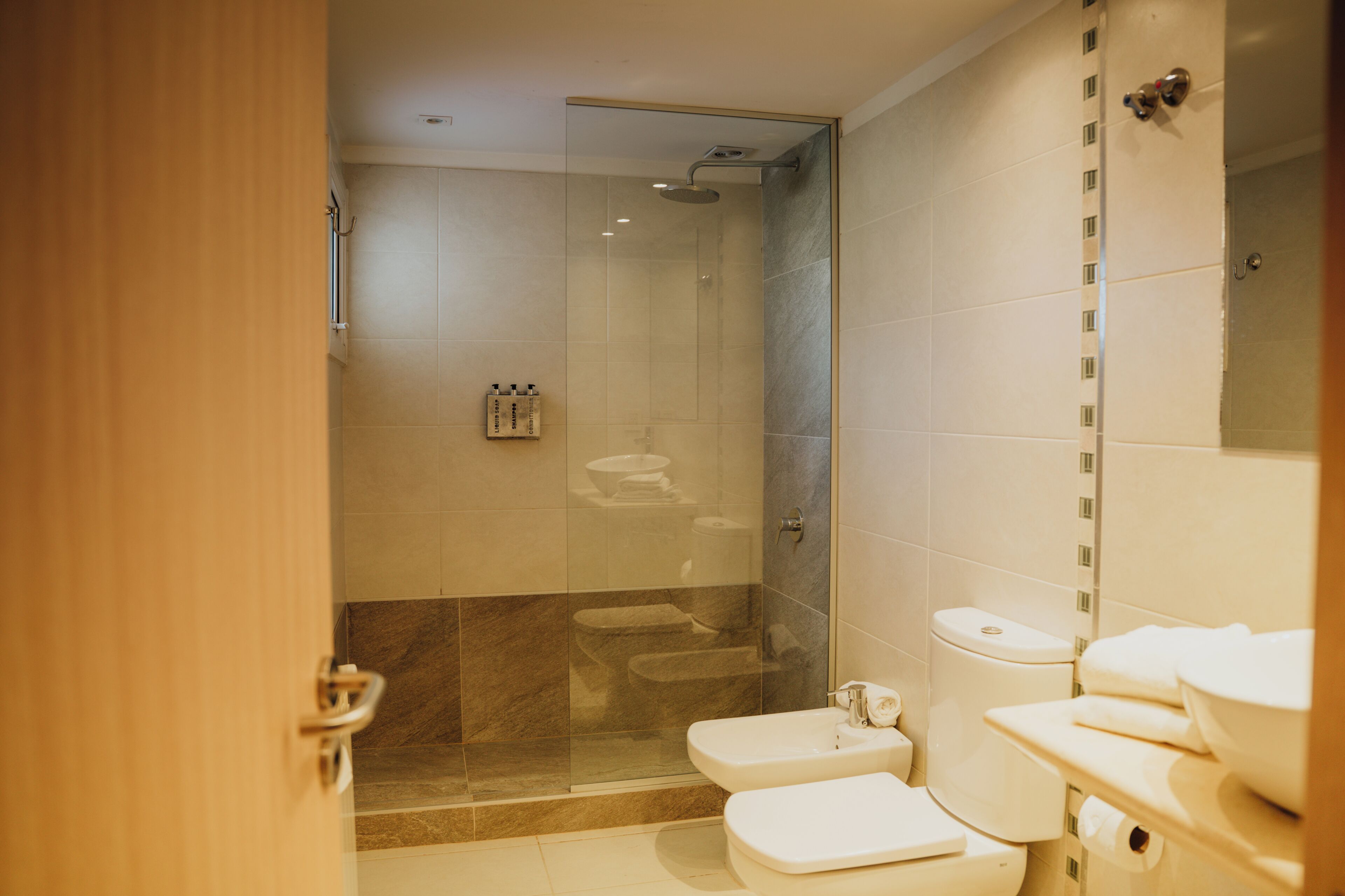 A modern bathroom with a glass-enclosed shower, a toilet, and a sink.