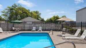 A swimming pool with lounge chairs and a covered patio area.