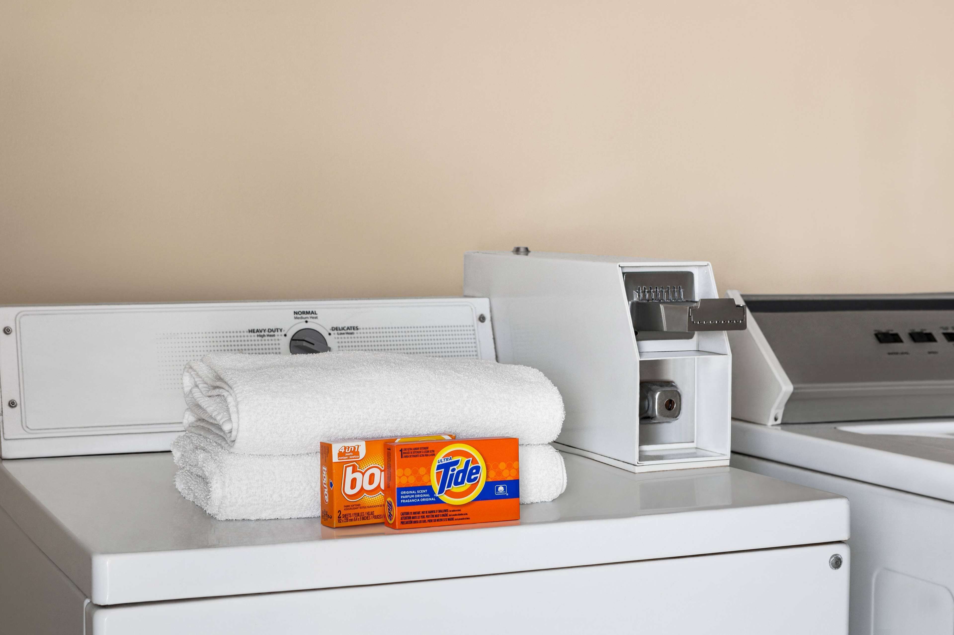 Una lavadora blanca con una caja de detergente Tide y una toalla blanca doblada encima.