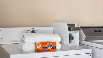 Una lavadora blanca con una caja de detergente Tide y una toalla blanca doblada encima.