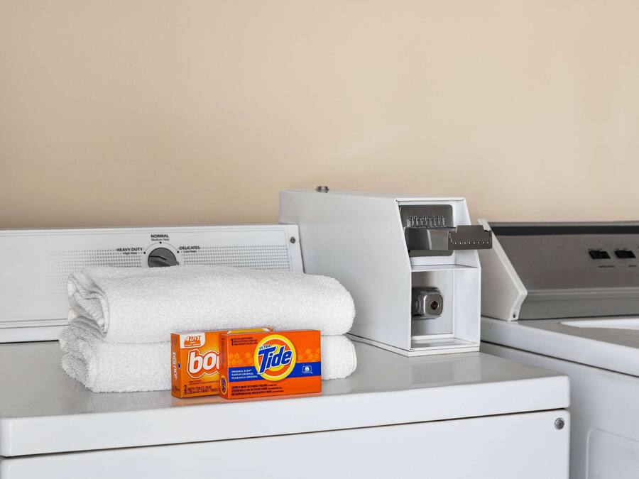 Una lavadora blanca con una caja de detergente Tide y una toalla blanca doblada encima.