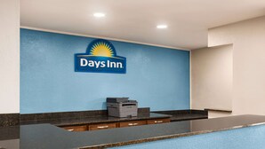A reception desk with a Days Inn sign, a printer, and a counter with drawers.