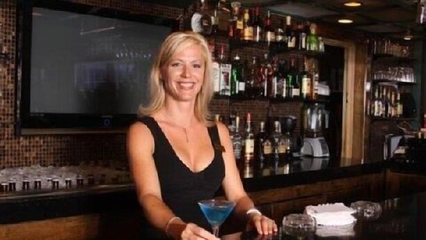 A bar area with a bartender holding a martini glass.