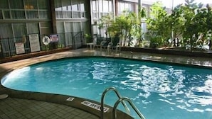 An indoor swimming pool with clear water, tiled floor, and metal pool ladders.