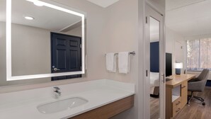 Un baño moderno con un espejo grande, lavamanos blanco y tocador de madera.