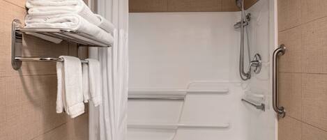 A modern bathroom with a shower, a towel rack, and a handrail.