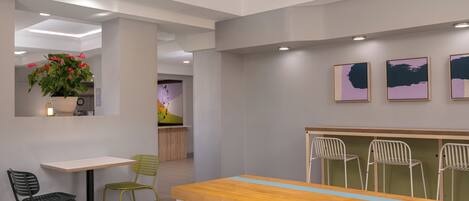 A modern dining area with a wooden table and chairs, a potted plant, and artwork on the wall.
