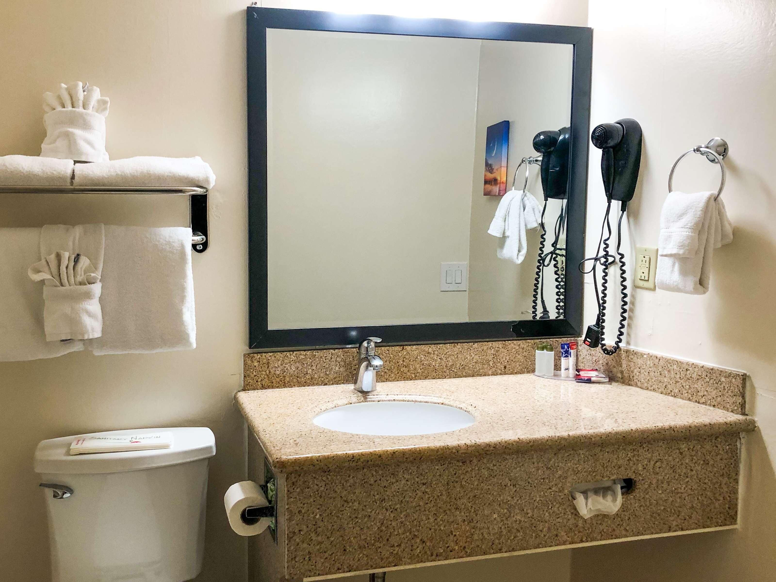 A bathroom with a sink, mirror, towel rack, and toilet.