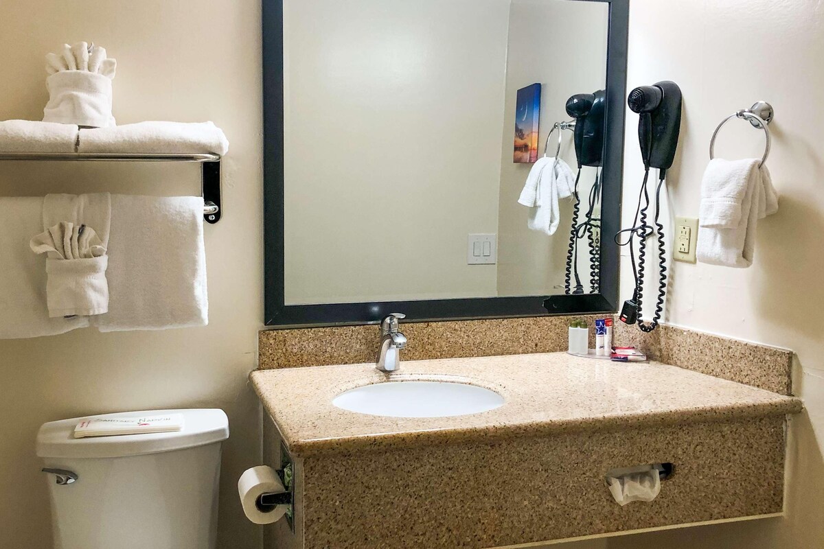 A bathroom with a sink, mirror, towel rack, and toilet.