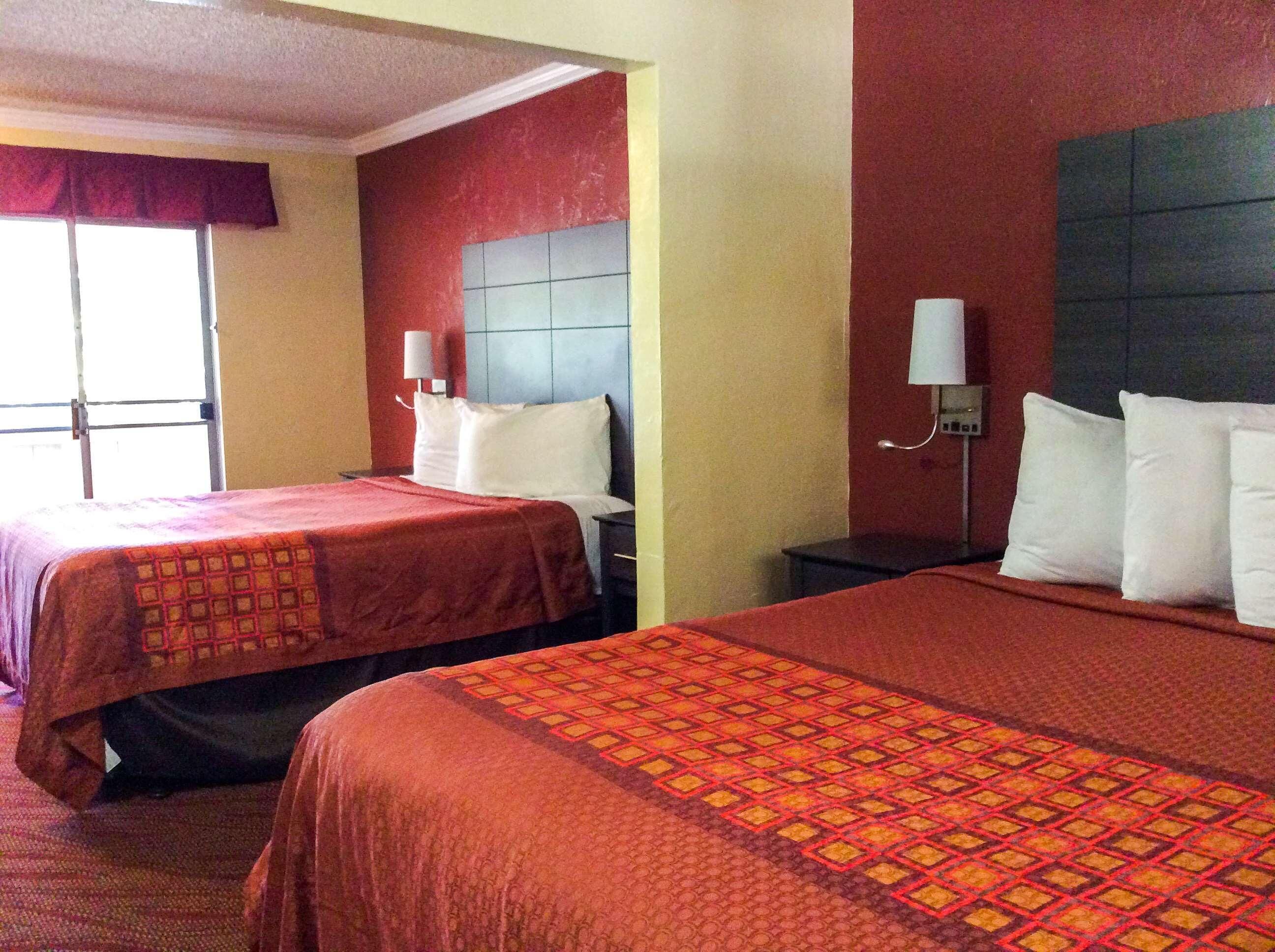 A hotel room with two beds, each with a headboard and a bedside table.