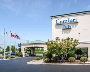 A Comfort Inn hotel with a large sign, a parking lot, and flags.