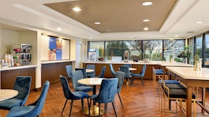 A modern cafe with round tables, blue chairs, and a coffee bar. - Comfort Inn Bellingham (Bellingham)