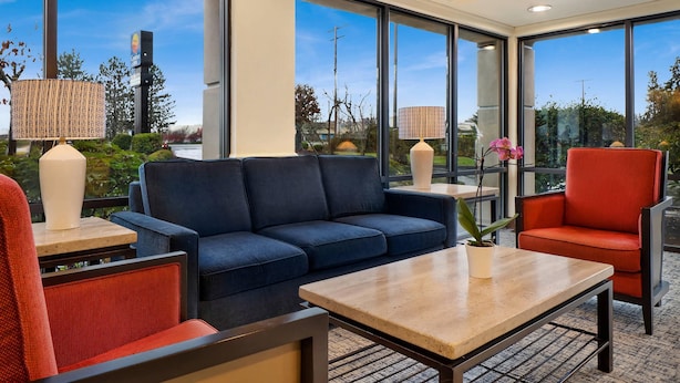 A modern hotel lobby with a blue sofa, red chair, and a wooden coffee table. - Comfort Inn Bellingham (Bellingham)