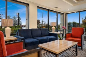 A modern hotel lobby with a blue sofa, red chair, and a wooden coffee table. - Comfort Inn Bellingham (Bellingham)
