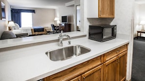 A hotel room with a kitchenette, including a sink, microwave, and wooden cabinets. - Comfort Inn Bellingham (Bellingham)