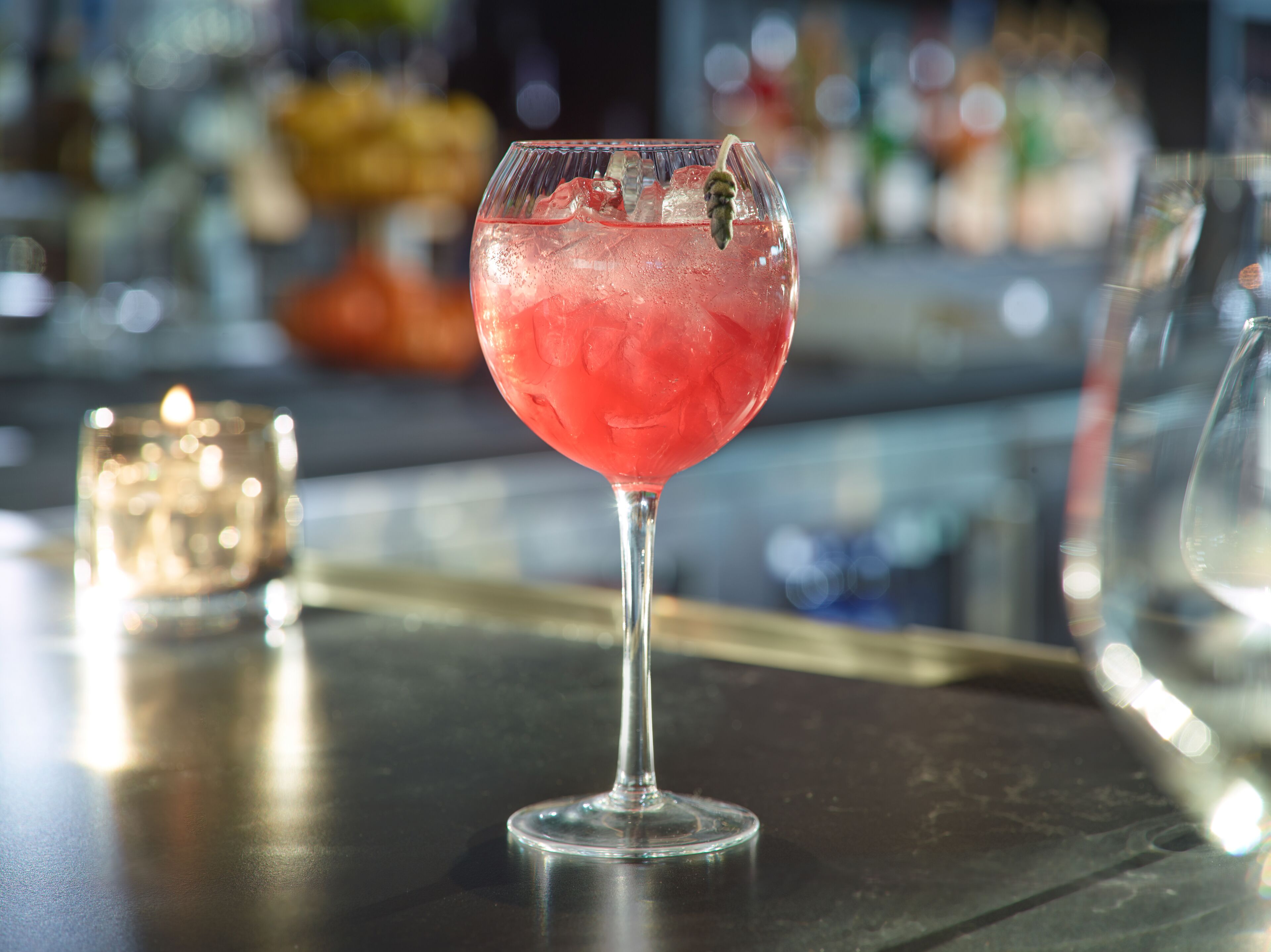 A cocktail glass with ice cubes on a bar counter.