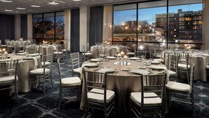 A banquet hall with round tables, chairs, and candles.