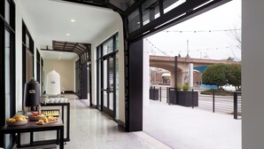 A corridor with a breakfast setup, including a coffee machine, pastries, and a fruit bowl.