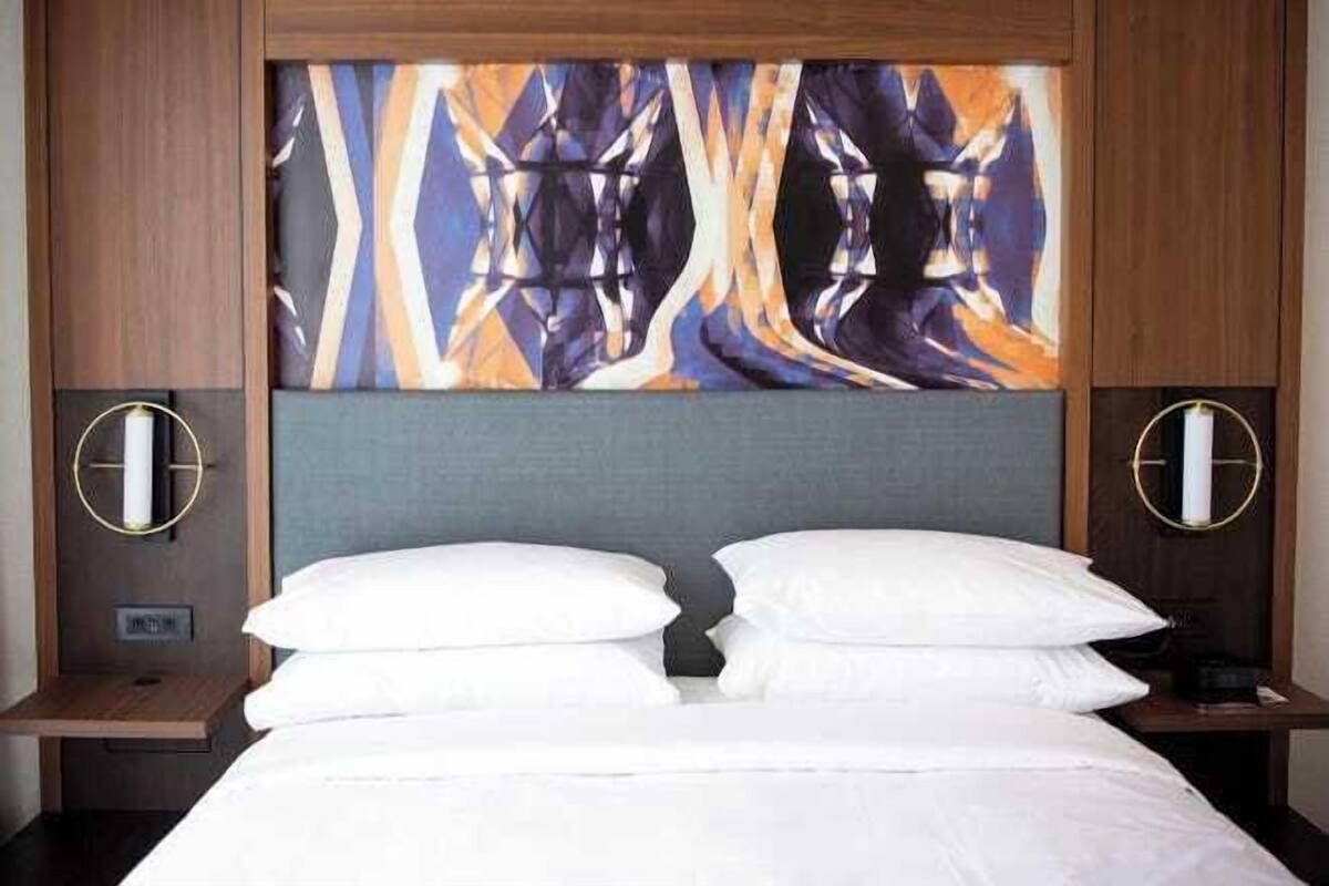 A hotel room with a large bed, two bedside tables, and a wall-mounted artwork.