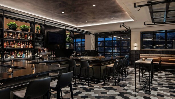 A bar area with a hexagonal tiled floor, a bar counter, and seating.