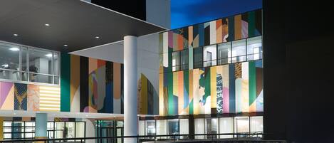 Ein modernes Gebäude mit großen Fenstern und farbenfrohen, geometrischen Mustern an der Fassade.