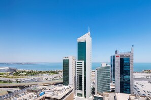 A high-rise building with a modern glass facade, adjacent to a body of water and other commercial buildings. - Four Points by Sheraton Kuwait (Kuwait City)
