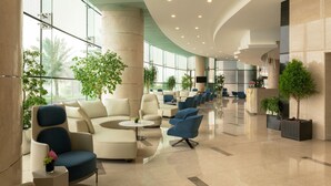 Eine großzügige Lobby mit gewölbter Decke, großen Fenstern und mehreren Sitzbereichen.