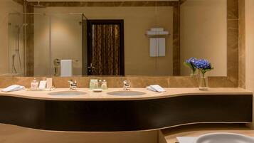 A modern bathroom with a curved vanity, two sinks, a large mirror, a shower area, and a bathtub.