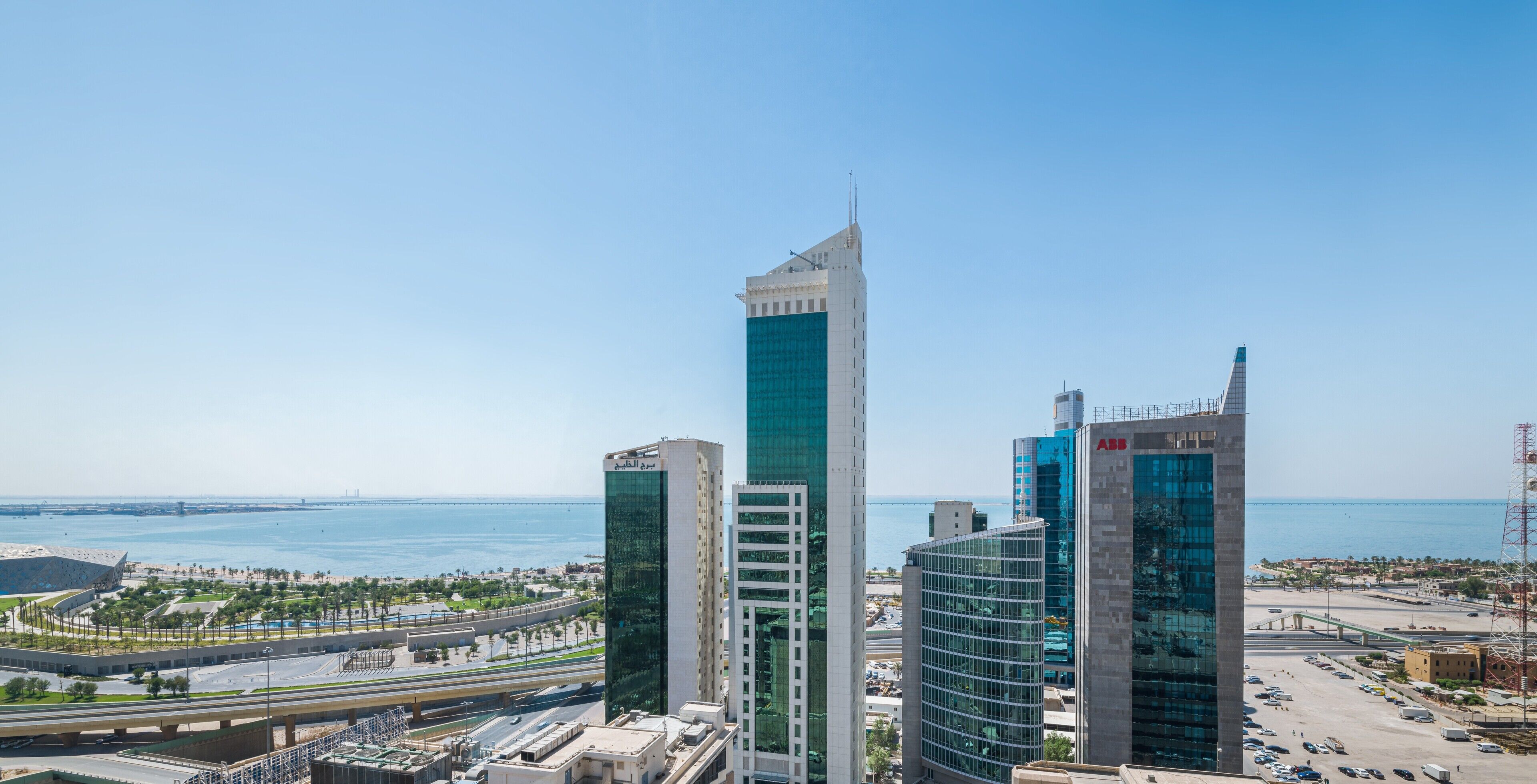 A cityscape with modern high-rise buildings, a bridge, and a body of water.