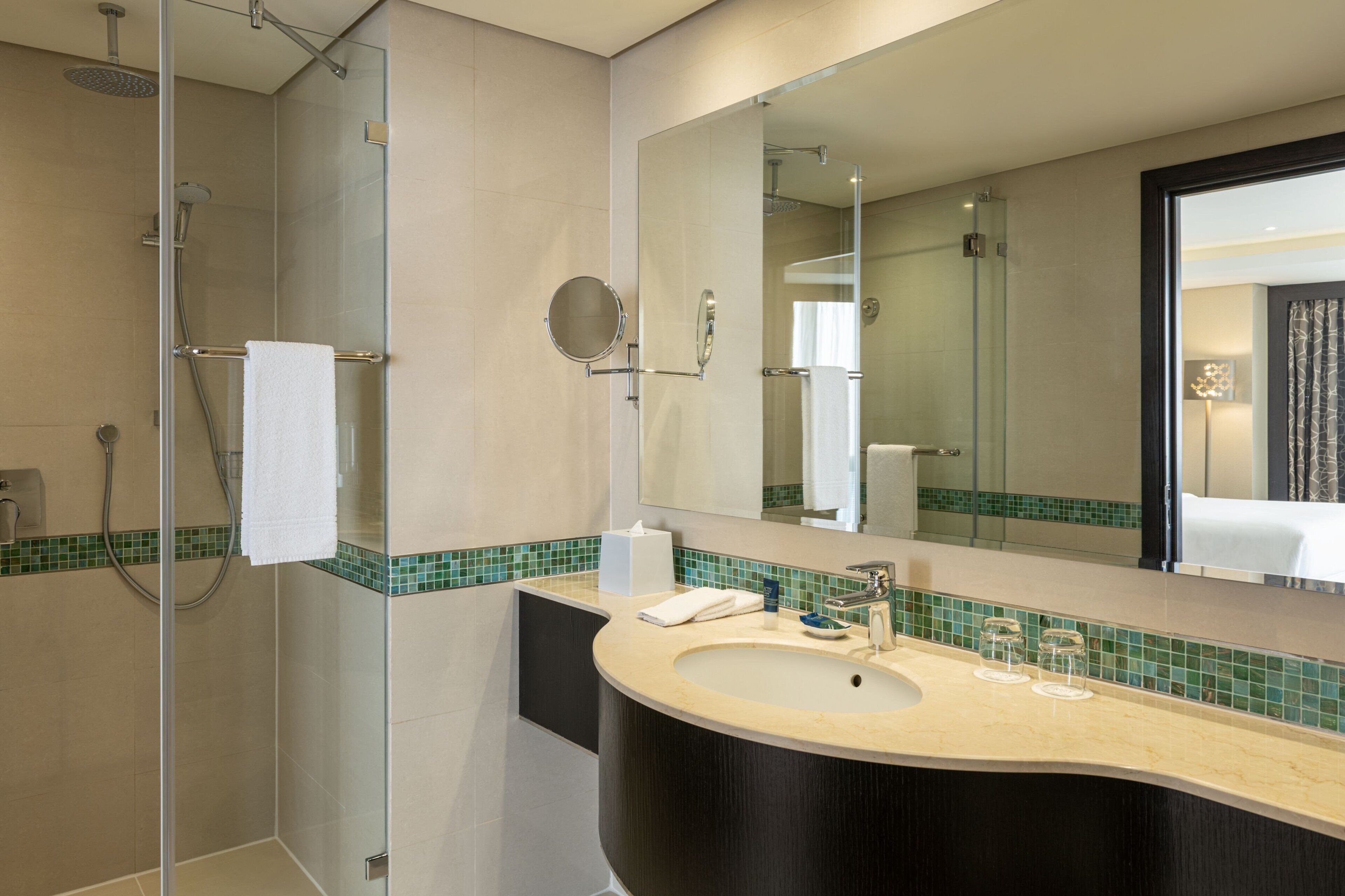 A modern bathroom with a glass-enclosed shower, a curved sink, and a large mirror.