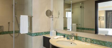 A modern bathroom with a glass-enclosed shower, a curved sink, and a large mirror.