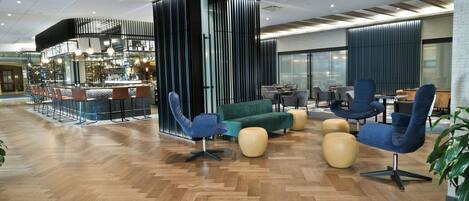 Un área de estar moderna con un bar, asientos y un piso de madera con patrón de espiga.