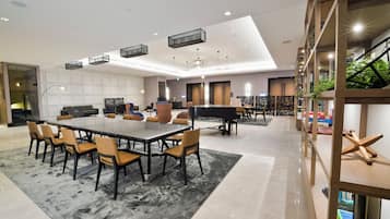 Relax in our elegant lobby, featuring a large dining table, comfortable seating, and a grand staircase.