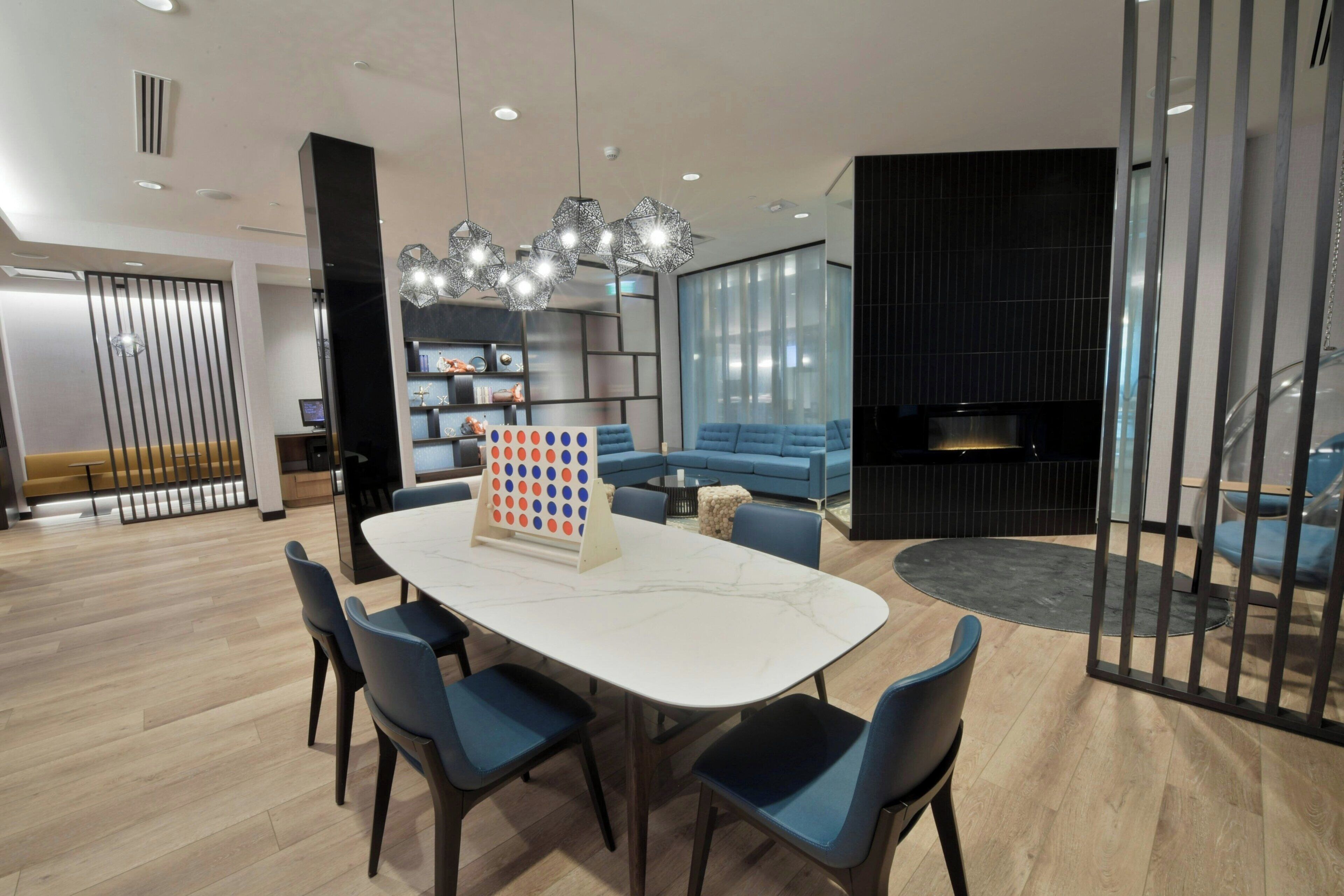 Ein modernes Wohnzimmer mit einem weißen Marmortisch, blauen Stühlen, einem schwarzen Ecksofa und einem Kamin.