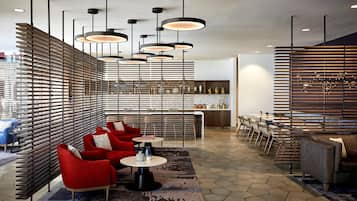 A modern interior with a bar area, red seating, and pendant lighting.