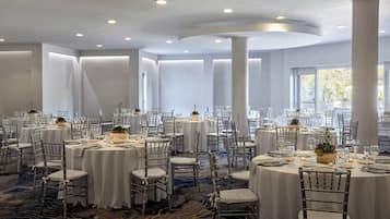 A banquet hall with round tables, white tablecloths, and chairs.