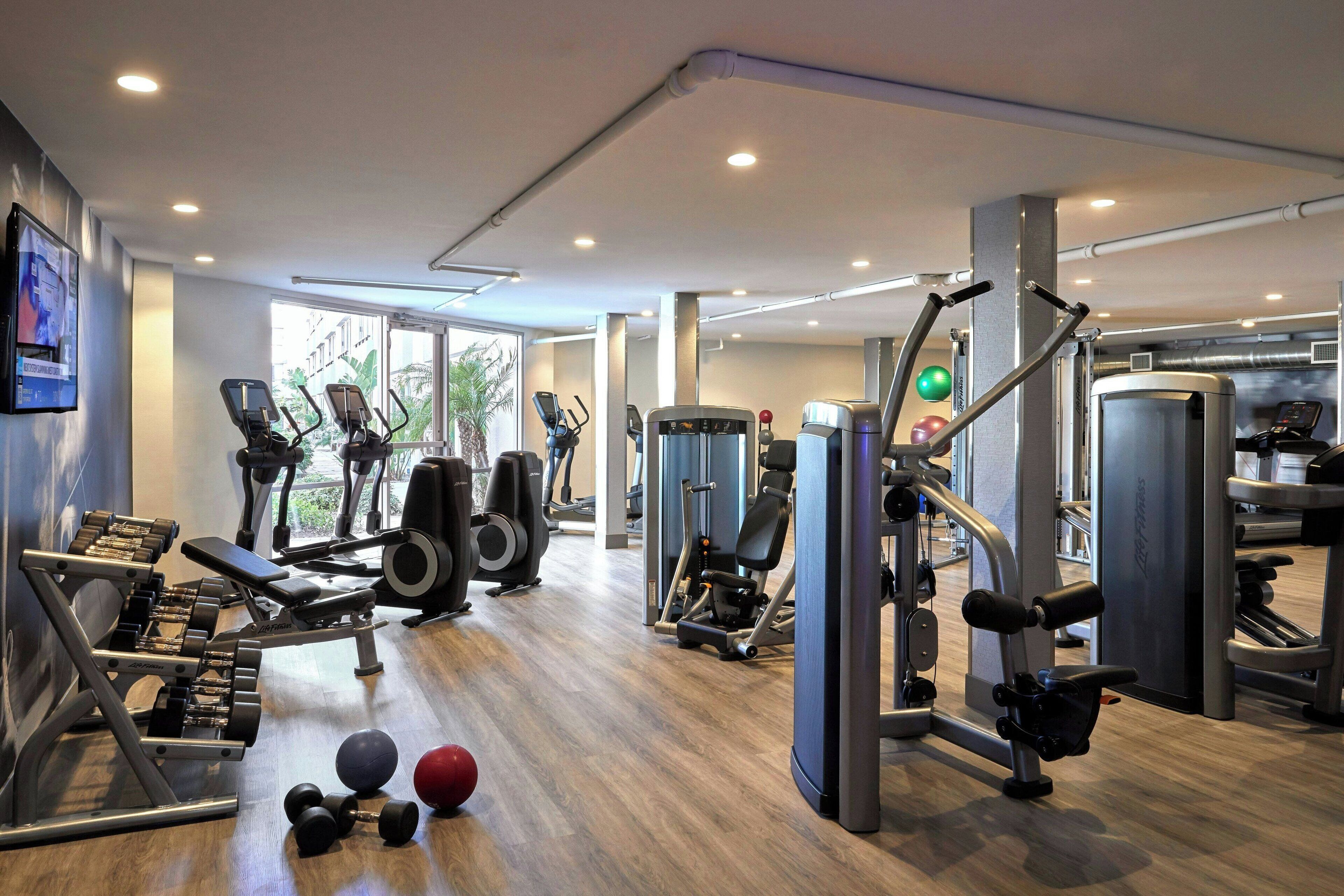 Een moderne sportschool met diverse fitnessapparaten, waaronder loopbanden, krachttrainingsmachines en gewichten.