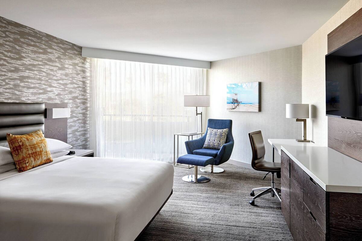 Une chambre d’hôtel avec un grand lit, un bureau, une chaise et un téléviseur.