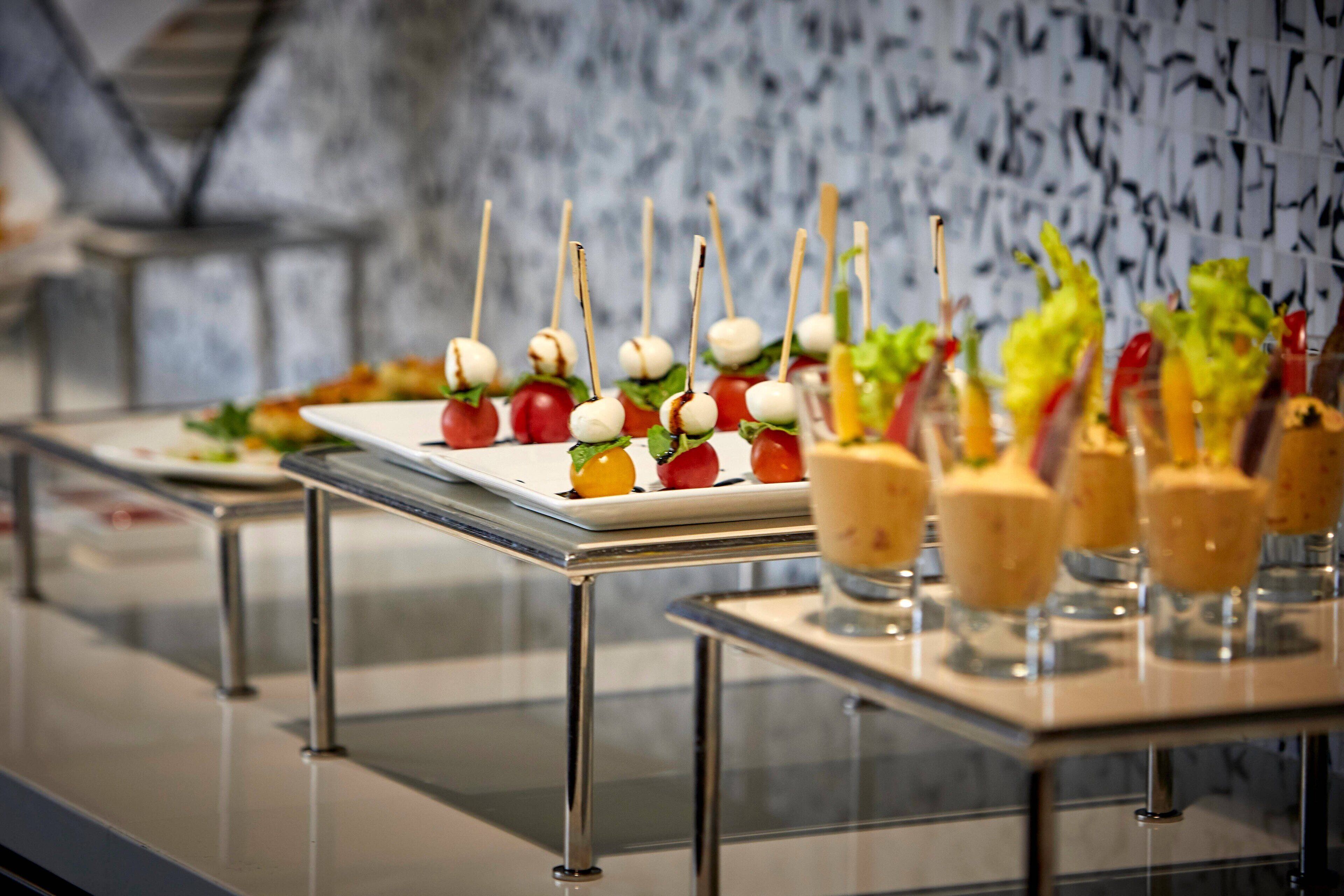 A buffet table with various food items, including skewers with tomatoes and mozzarella, and other dishes.