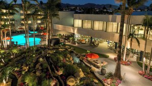 Un patio de hotel con piscina, palmeras y un jardín ajardinado.