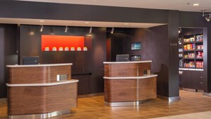 A reception area with two wooden reception desks, a red accent wall, a television, and a snack vending machine.