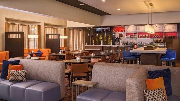 A hotel lobby with seating areas, a bar, and a television screen.