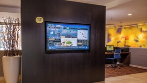 A modern reception area with a digital display on a wall, a reception desk, and a decorative plant.