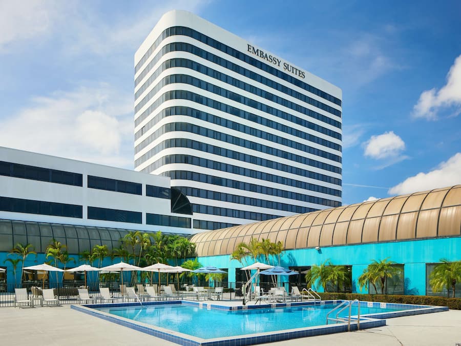 Un hotel moderno con piscina, sillas de descanso y sombrillas.
