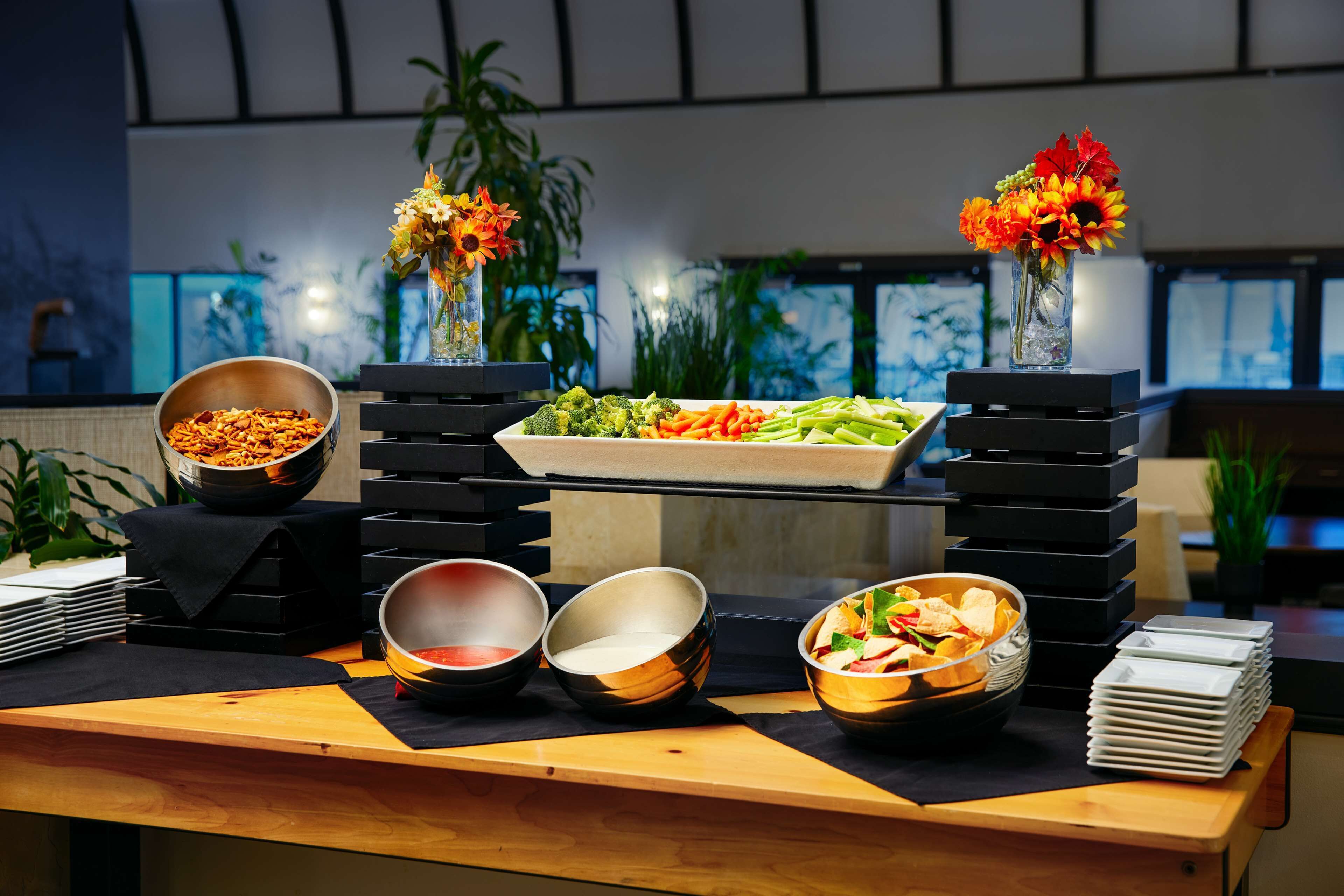 A buffet setup with various food items and a decorative vase with flowers.