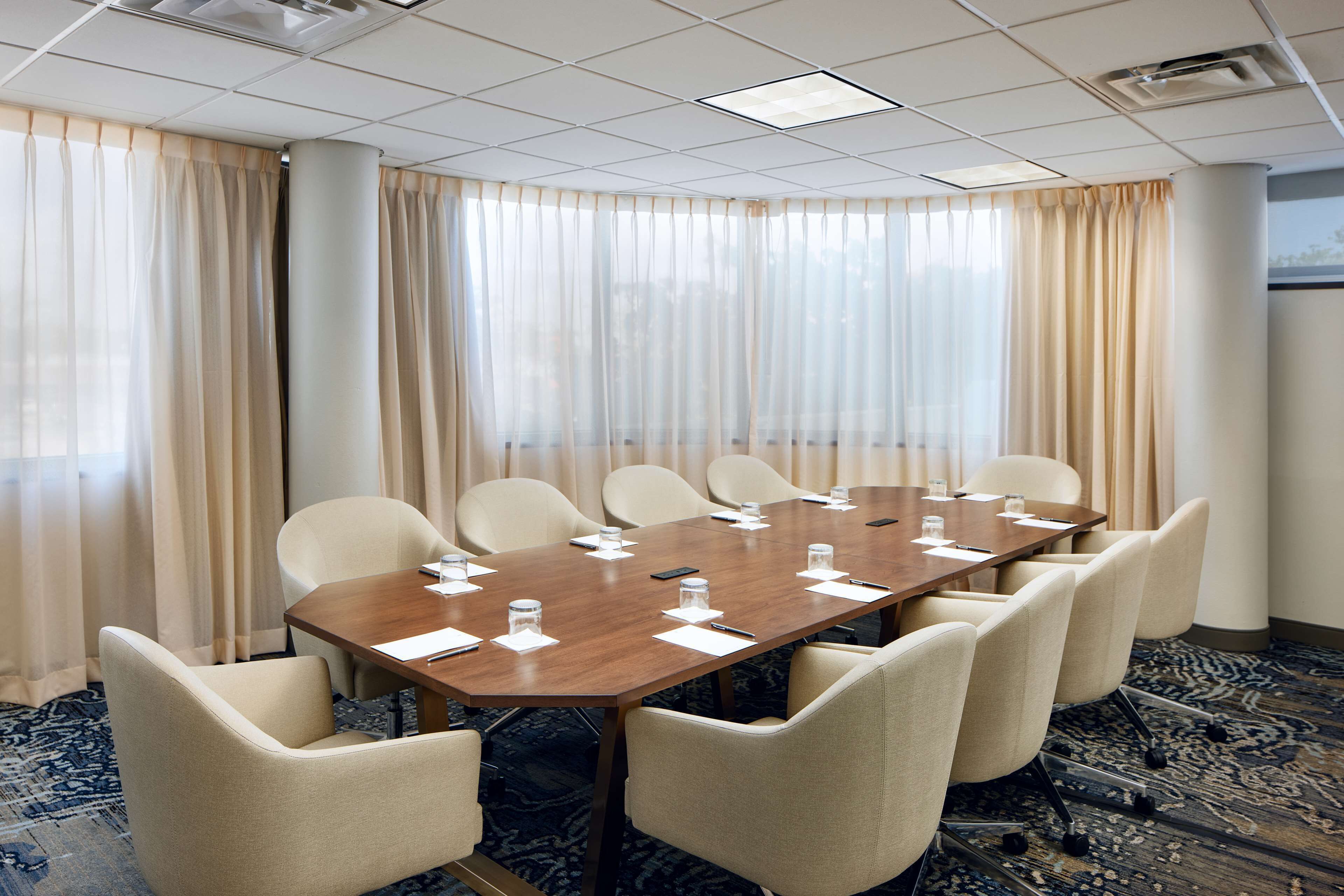 Una sala de conferencias con una larga mesa, seis sillas y suelo alfombrado.