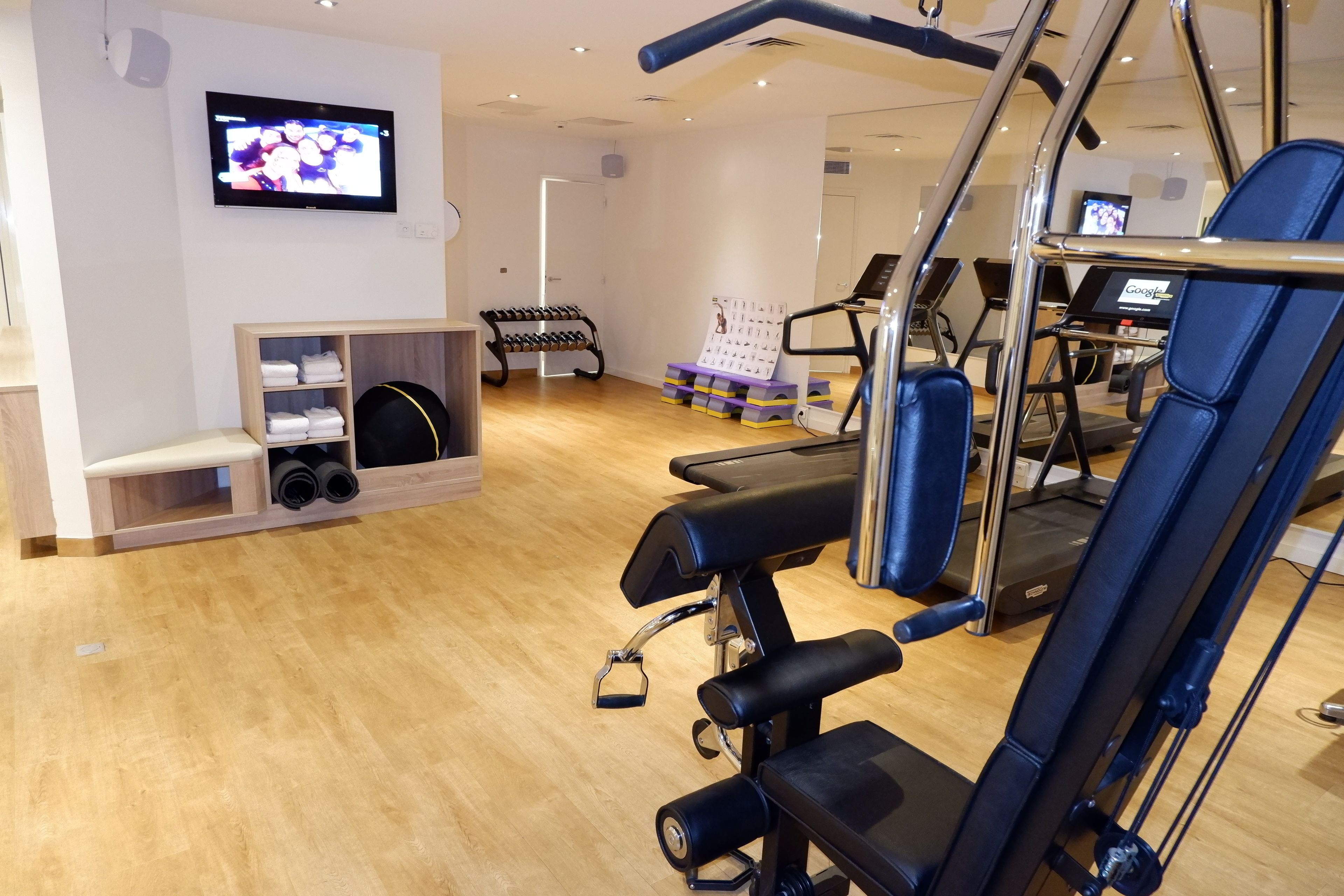 A gym with exercise equipment, a television, and a shoe rack.