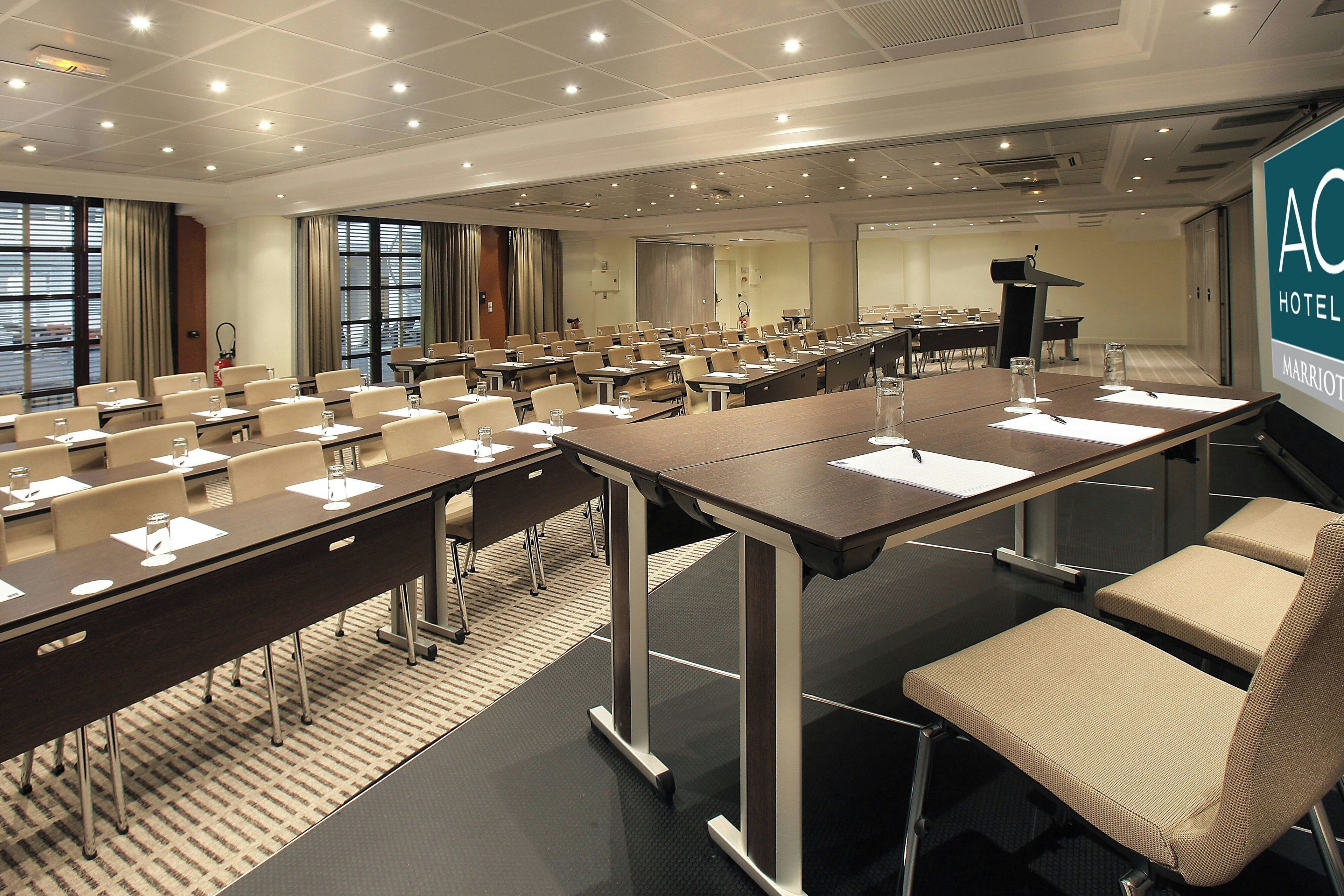 A conference room with multiple tables and chairs, equipped with nameplates and water glasses.