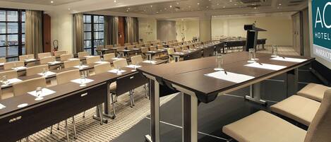 A conference room with multiple tables and chairs, equipped with nameplates and water glasses.