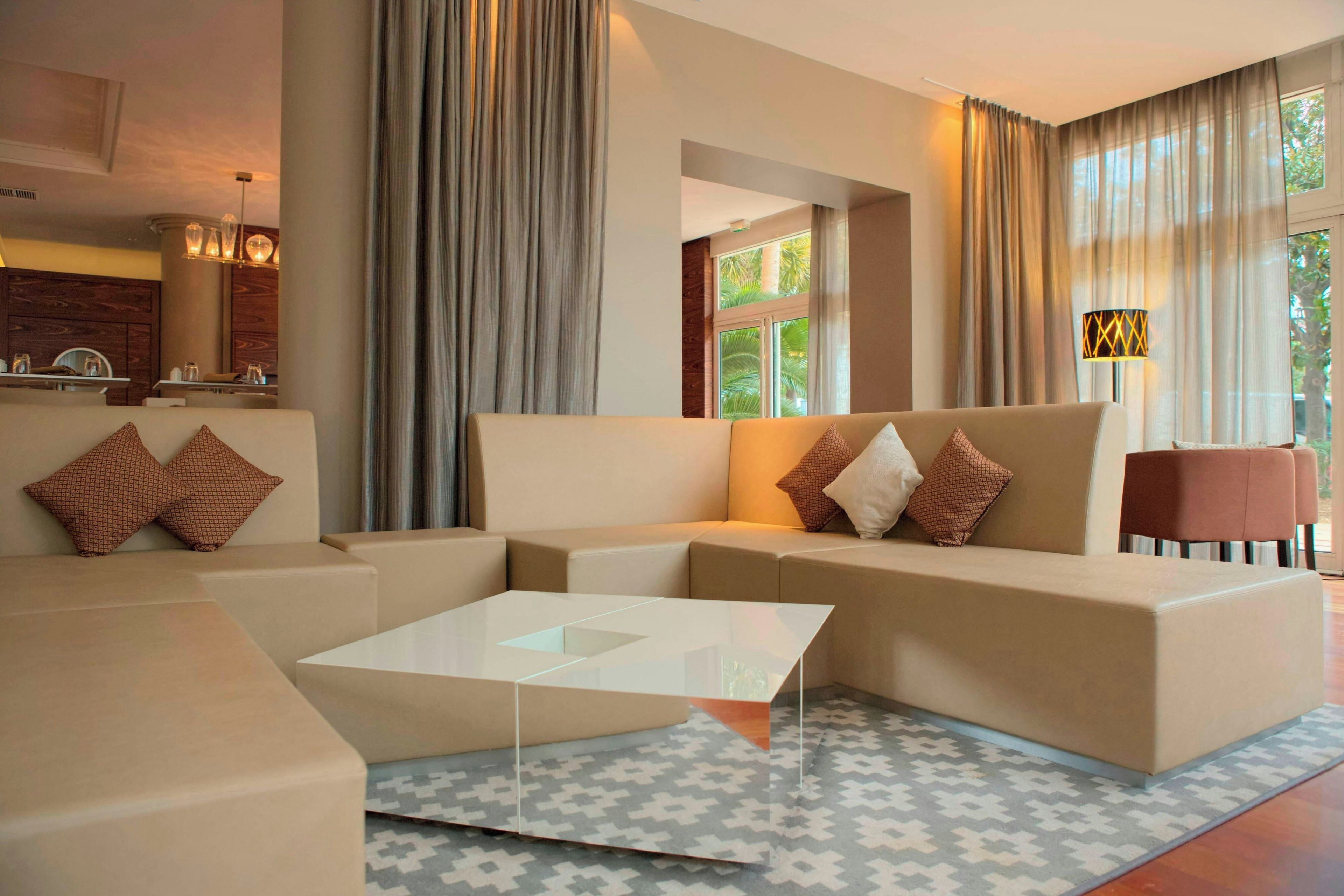 A modern living room with a sectional sofa, a glass coffee table, and a patterned rug.